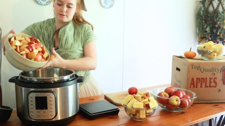 woman with green baby wrap adding chopped apples into large instant pot