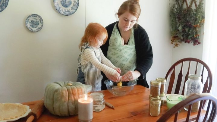 redhead toddler and woman in black sweater and green baby wrap crack into glass mixing bowl