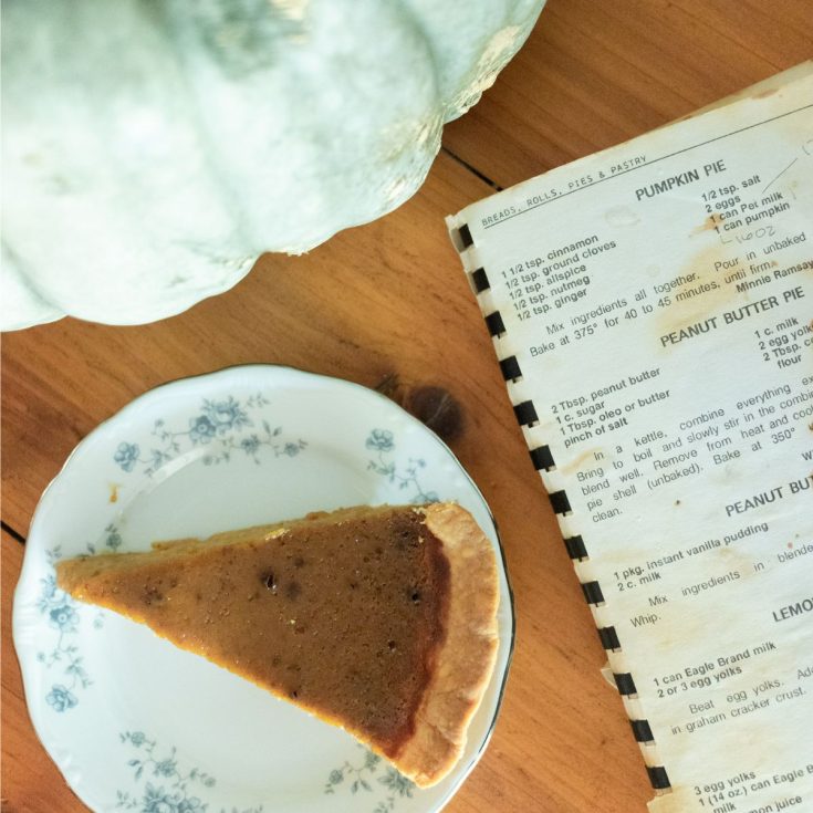 green jarahdel pumpkin, old community cookbook and a slice of pumpkin pie on a blue floral plate